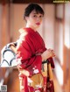 A woman in a red kimono is posing for a picture.