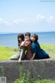 A group of three women sitting on top of a cement wall.