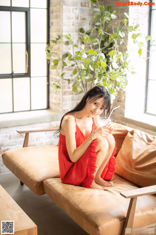 A woman in a red dress sitting on a couch.