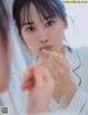 A woman brushing her teeth in front of a mirror.