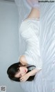 A woman laying on top of a bed in a white dress.