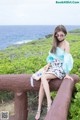 A woman sitting on a bench near the ocean.