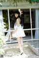 A woman in a white dress standing on a wooden deck.