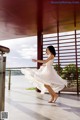 A woman in a white dress is dancing on a balcony.