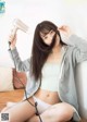 A woman sitting on a couch holding a hair dryer.