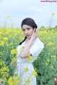 A woman in a field of yellow flowers talking on a cell phone.