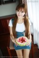 A woman sitting on a chair holding a slice of watermelon.