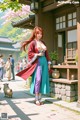 A woman in traditional attire stands outside a building with cherry blossoms and people in the background.