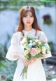 A woman in a white dress holding a bouquet of flowers.