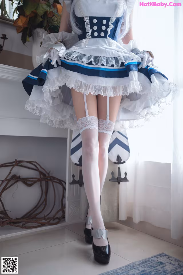 A woman in a blue and white dress is posing for a picture.