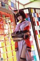 A woman in a kimono standing in front of a stained glass window.