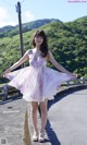 A woman in a dress standing on the side of a road.