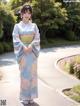 A woman in a blue kimono standing on a sidewalk.