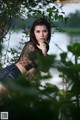 A woman sitting on a bench in front of a lake.